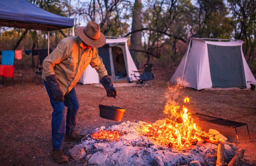 Adventure Wild Kimberley Tour guide Phil is campfire cooking at our permanent campsite, Manning River, Mt Barnett Station