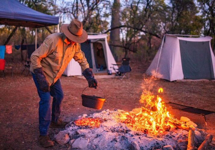 Adventure Wild Kimberley Tour guide Phil is campfire cooking at our permanent campsite, Manning River, Mt Barnett Station